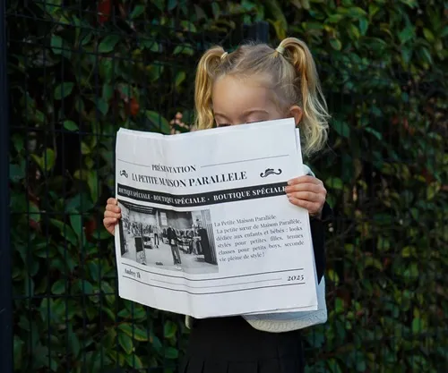 Petite fille qui tient une photo avec un journal au nom de La petite maison parallèle